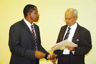 Thakkar (R) handing over some documents to CPA Derick Nkajja